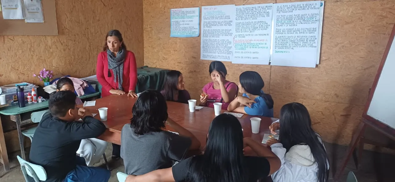 Catequista y jóvenes reunidos alrededor de una mesa en una clase de catequesis de Primera Comunión