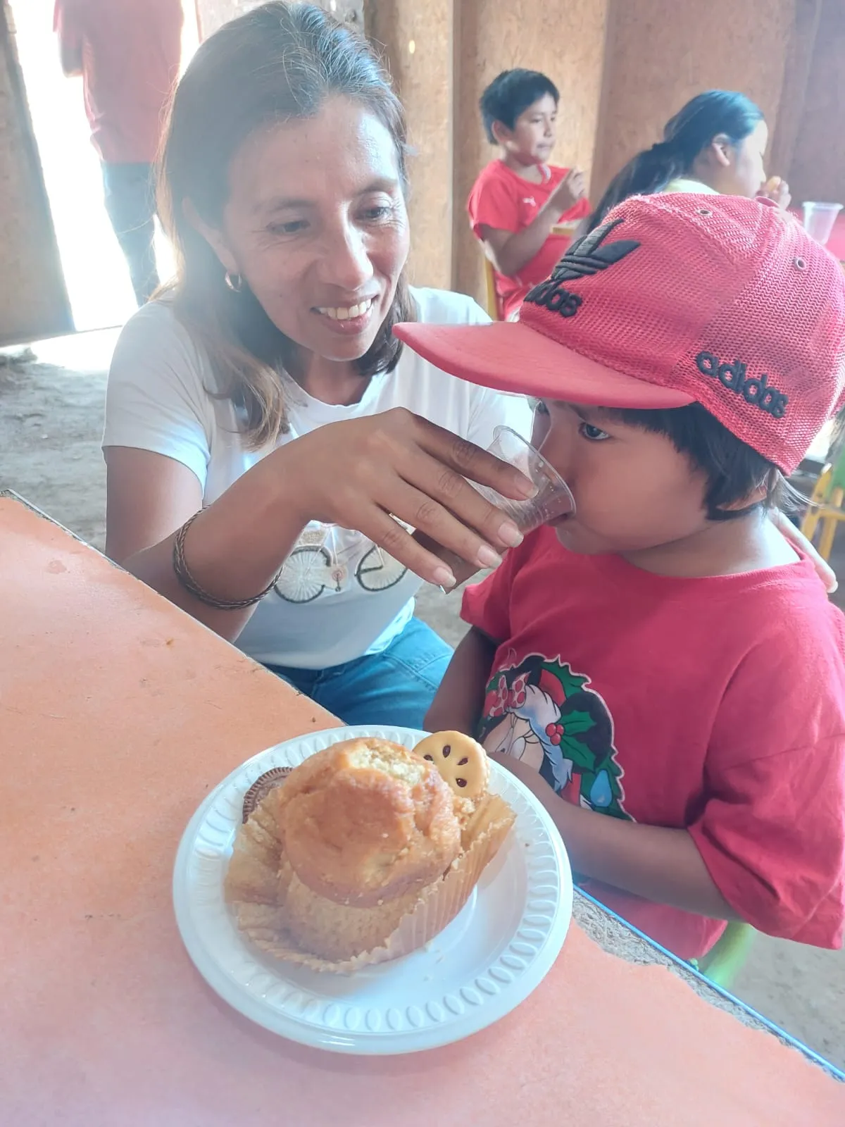 Voluntaria compartiendo una merienda con un niño en una reunión de perseverancia